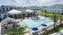 Pool with sundeck filled with lounge chairs and tables.