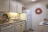 Kitchen with tile floors, beige cabinets, and white appliances.