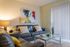 Carpeted living room with closed blinds, wall art, coffee table, two couches, and an end table with a lamp.