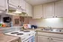 Kitchen with beige cabinets, stainless steel sink, white stove, lights under cabinets and a passthrough to the living room.