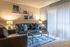 Carpeted living room with closed blinds, wall art, coffee table, two couches, and an end table with a lamp.