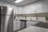 Kitchen with wood style floor, white cabinets, stainless steel appliances, white subway tile, white quartz countertops, a coffee machine and other items.