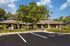 Leasing office exterior with large tree. Parking lot in foreground.