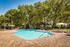 Community pool with lounge chairs, tables, and umbrellas.