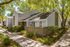 Apartment exterior with brick half wall. Shaded sidewalk along exterior.