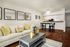 Living room with cream couch and coffee table. Dining set and breakfast bar visible in background.