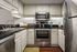 Kitchen with black granite countertop, white classic cabinets, and stainless steel oven and fridge
