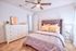 Carpeted bedroom with white walls, large windows, and white bedding.