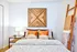 Carpeted bedroom with white walls, large windows, and white bedding.