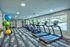 Fitness center with various cardio equipment and wall mounted television.  Mirrored wall in the background.
