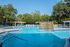Large community pool with lounge chairs, clubhouse and leasing office in the background.