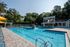 Large community pool with lounge chairs, clubhouse and leasing office in the background.