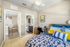 Another bedroom with blue and white bedspread.  Desk and chair on the right.  Large window with open horizontal blinds.