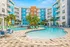 Community pool area with hammock in foreground, green lounge chairs and residential buildings in the background.