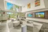 Community clubhouse with modern couch loaded with pillows.  Leasing offices behind glass walls in background.