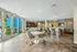 Community clubhouse with modern couch loaded with pillows.  Leasing offices behind glass walls in background.