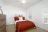 Carpeted bedroom with bed with red bedspread
