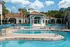 Large community pool lined with lounge chairs.  Covered basketball court and clubhouse in background.