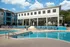Large community pool lined with lounge chairs.  Covered basketball court and clubhouse in background.