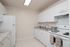 Galley kitchen with white cabinets, double sink, and white refrigerator and stove..