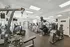 Community fitness center with various exercise equipment and ceiling mounted televisions.