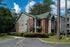 Inviting suburban apartment building with brick and siding exterior surrounded by lush greenery.