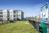 Modern apartment building with pet-friendly amenities, fenced green area, and convenient pet waste station, perfect for pet owners.