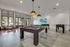 Modern entertainment room featuring a sleek pool table, cozy seating, and a vibrant wall-mounted TV, perfect for relaxation and fun.