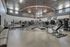 Spacious and modern fitness center equipped with state-of-the-art machines, free weights, and exercise equipment, framed by a striking geometric ceiling design.