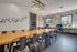 Modern conference room with rustic accents, featuring a long wooden table, industrial chairs, creative lighting, and large windows offering natural light.