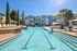 Luxurious apartment complex with a stunning outdoor pool, surrounded by elegant loungers and lush palm landscaping, offering resort-style living.