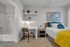 Elegant bedroom with plush bedding, modern desk area, and an inviting en-suite bathroom, accentuated by warm lighting and chic decor.