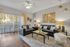 Modern living room bathed in natural light with sleek black leather sofas, chic decor, and a serene outdoor view through large glass doors.