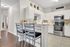 Charming kitchen with sleek white cabinets, modern stainless steel appliances, and a cozy breakfast bar adorned with stylish decor.