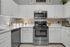 Modern kitchen with sleek stainless steel appliances, elegant white cabinetry, and charming decor, creating a warm and inviting atmosphere.