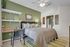 Cozy bedroom with a stylish green accent wall, chic shelving, and a comfortable queen-sized bed.