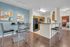 Modern open-plan kitchen and dining area with sleek black appliances, accented by a vibrant blue feature wall and contemporary art.