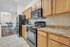 Modern kitchen with spacious countertops, wood cabinetry, and sleek black appliances, opening into a cozy breakfast nook with elegant dining setup.
