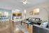 Modern open-concept living room with elegant black leather sofas, stylish dining area, and a sleek kitchen bar.