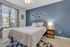Inviting bedroom with a modern blue accent wall, cozy queen-size bed, and stylish decor, offering a relaxing retreat with ample natural light from large windows.