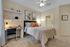Inviting bedroom with a cozy ambiance, featuring a well-lit workspace, elegant decor, and luxurious bedding.