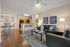 Chic open-concept living room with a sleek black leather sofa, modern decor, and a kitchen with a breakfast bar, perfect for stylish entertaining.