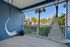 Charming balcony with stylish hanging chairs, offering a relaxing view of lush greenery and palm trees.