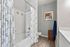 Elegant bathroom with modern fixtures, featuring a patterned shower curtain, chic artwork, and a cozy towel setup.