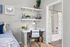 Charming bedroom nook with a cozy workspace, featuring stylish decor, modern shelving, and a glimpse of a sleek bathroom with elegant fixtures.