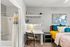 Cozy bedroom with modern decor featuring a comfortable bed adorned with colorful pillows, a sleek study nook with a lamp and decorative globe, and an adjacent bathroom with stylish shower curtains.