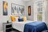 Bright and stylish bedroom with modern art, cozy bedding, and a large window offering natural light.