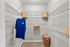 Spacious walk-in closet with wire shelving, featuring a vibrant blue shirt and decorative pillows.