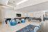Modern communal entertainment area featuring plush blue chairs, a foosball table, wall-mounted TV, and spacious pool table, perfect for relaxation and socializing.