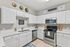 Bright, modern kitchen with white cabinetry, stainless steel appliances, and decorative wall accents, creating a welcoming and stylish atmosphere.